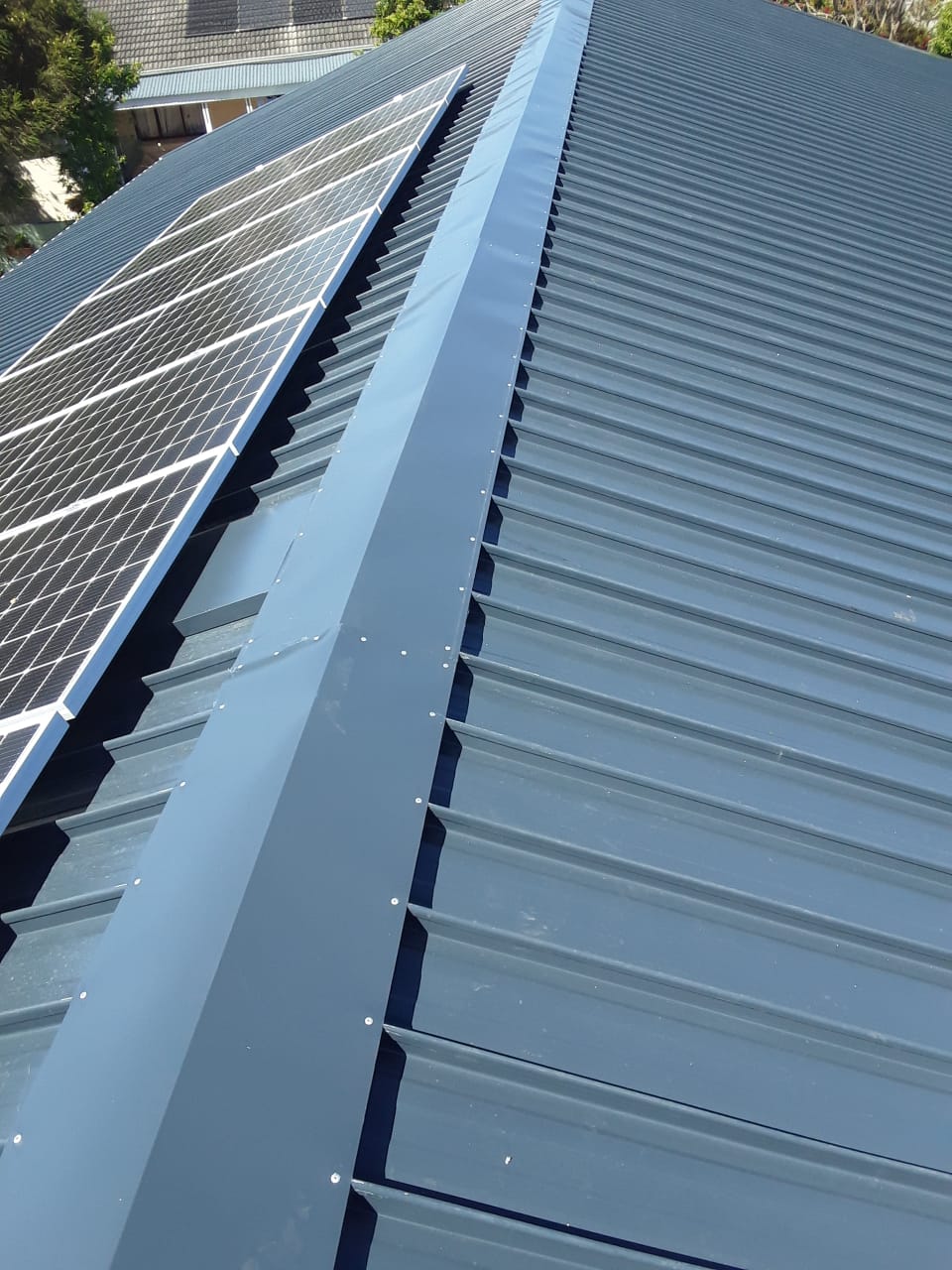 Finished metal roof flashing beside solar panels